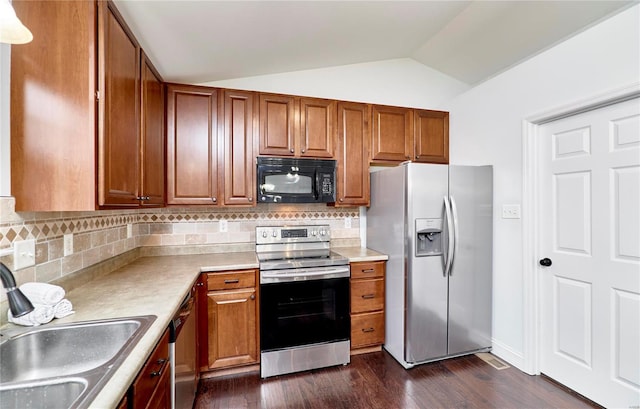 kitchen featuring dark wood-type flooring, a sink, appliances with stainless steel finishes, brown cabinetry, and vaulted ceiling