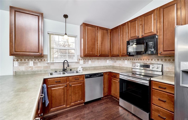 kitchen featuring brown cabinetry, dark wood finished floors, appliances with stainless steel finishes, and a sink