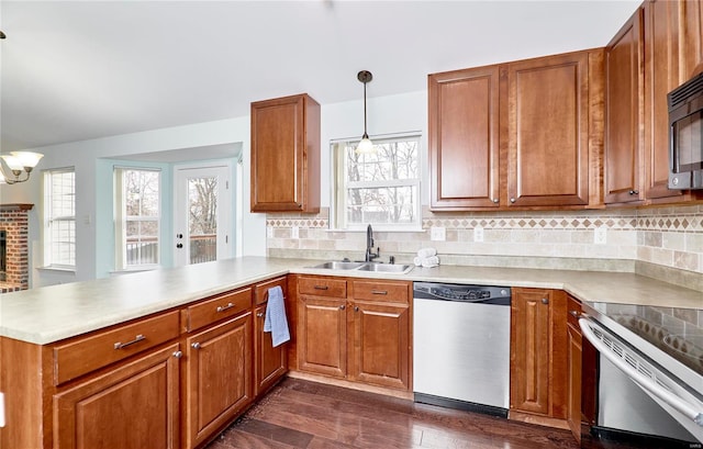 kitchen featuring electric range, brown cabinets, a sink, stainless steel dishwasher, and a peninsula