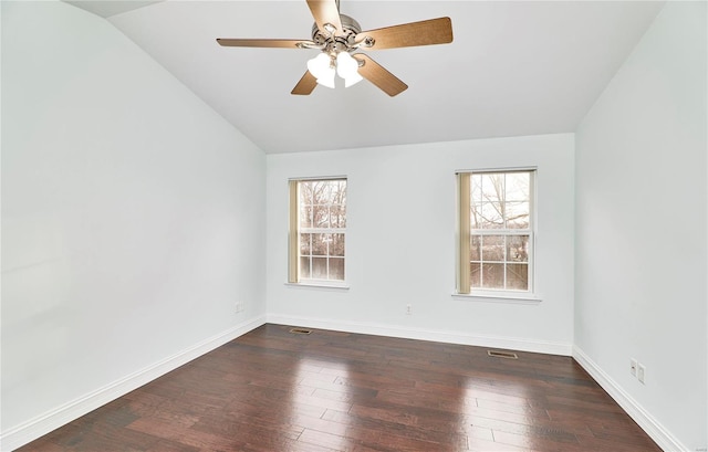 empty room featuring vaulted ceiling, plenty of natural light, baseboards, and dark wood-style flooring