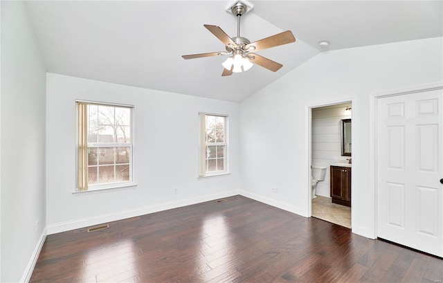 unfurnished bedroom with baseboards, visible vents, dark wood-type flooring, vaulted ceiling, and ensuite bathroom