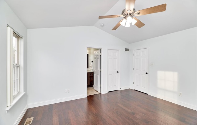 unfurnished bedroom with visible vents, lofted ceiling, dark wood-type flooring, and baseboards