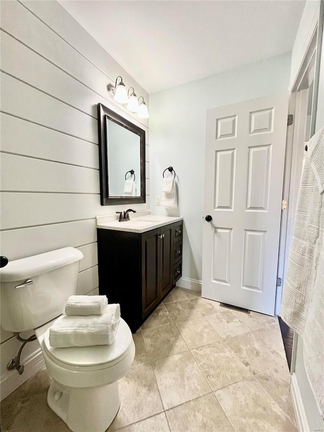 bathroom featuring vanity, toilet, baseboards, and tile patterned flooring