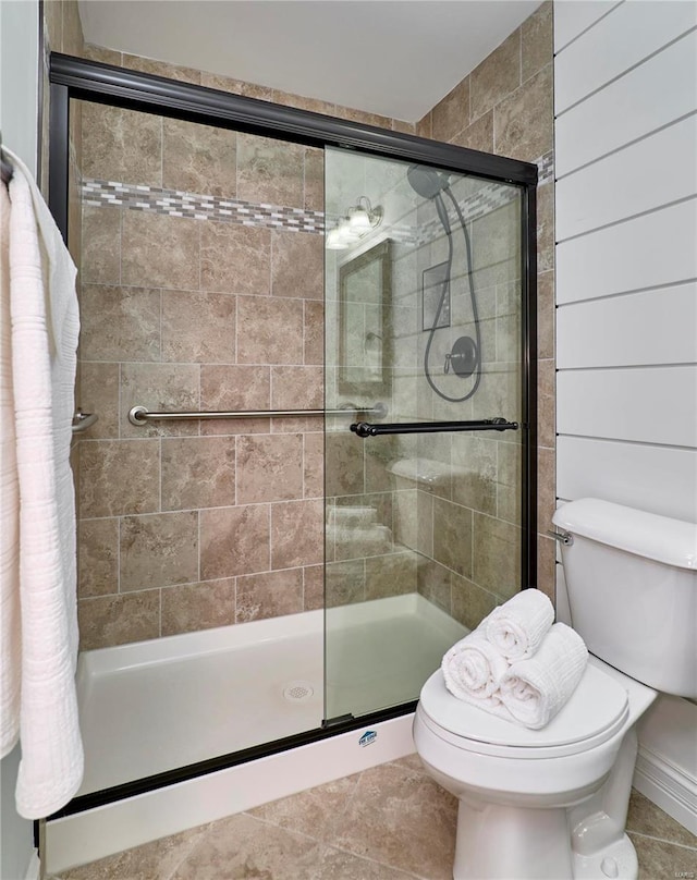 bathroom featuring tile patterned floors, a stall shower, and toilet