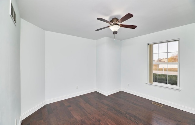 empty room featuring visible vents, baseboards, and dark wood-style flooring