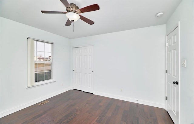 spare room featuring visible vents, a ceiling fan, dark wood-type flooring, and baseboards