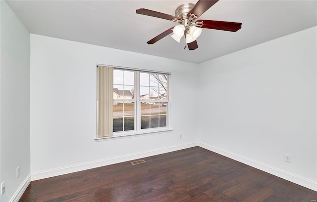 spare room with dark wood finished floors, baseboards, visible vents, and a ceiling fan