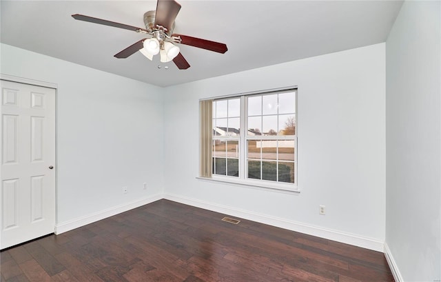 unfurnished room featuring dark wood finished floors, visible vents, a ceiling fan, and baseboards