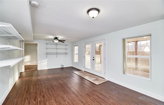 unfurnished living room featuring dark wood-style floors, plenty of natural light, baseboards, and ceiling fan