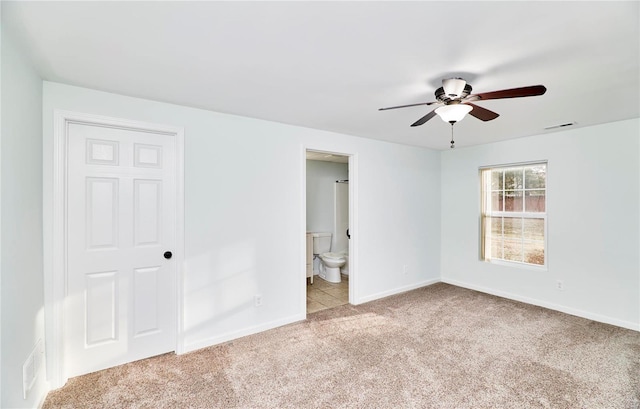 carpeted spare room featuring baseboards, visible vents, and ceiling fan