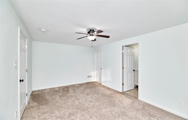 empty room with visible vents, a ceiling fan, baseboards, and light carpet