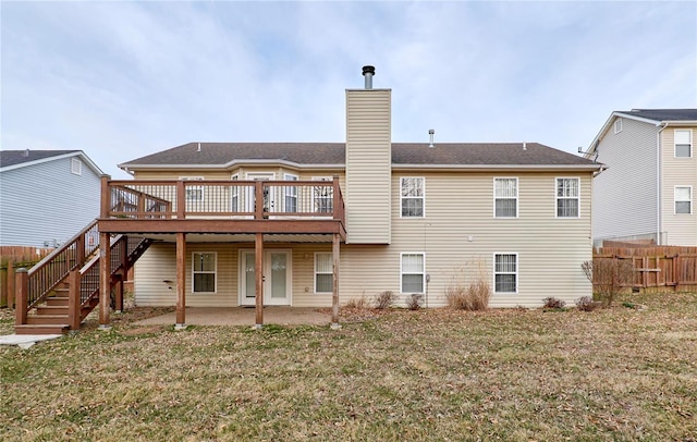 rear view of house featuring fence, stairway, a chimney, a deck, and a patio