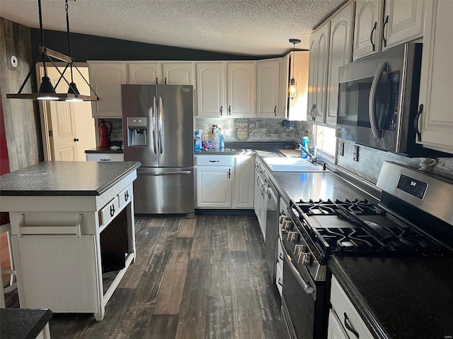 kitchen with a sink, dark countertops, appliances with stainless steel finishes, white cabinets, and dark wood-style flooring