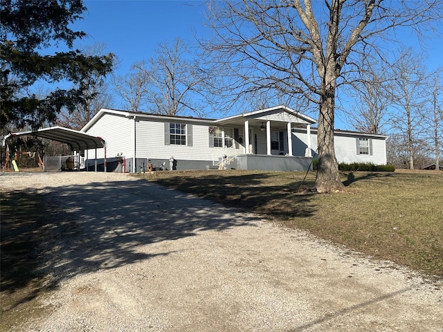 manufactured / mobile home with a porch, a carport, a front yard, and dirt driveway