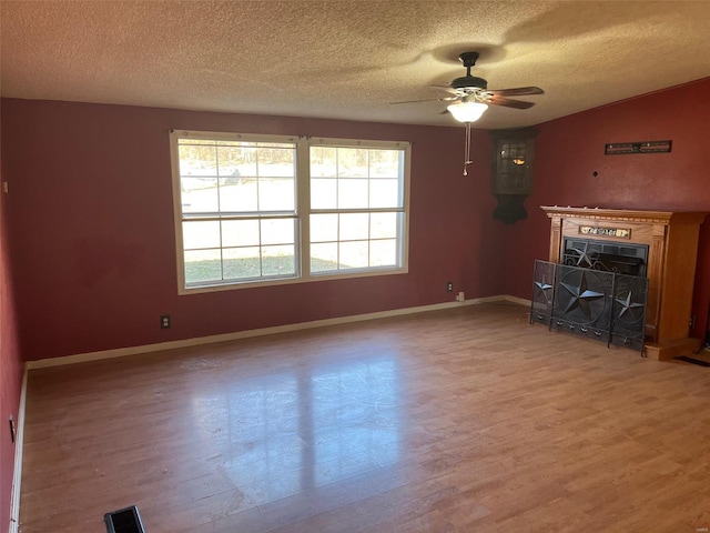 unfurnished living room with visible vents, baseboards, a fireplace, wood finished floors, and a ceiling fan