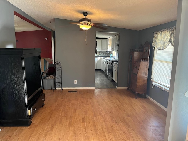 kitchen featuring visible vents, a ceiling fan, wood finished floors, range with gas cooktop, and white cabinets