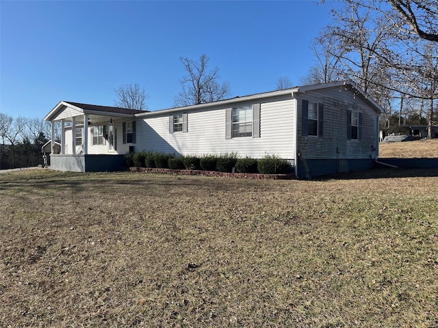 manufactured / mobile home with covered porch and a front lawn