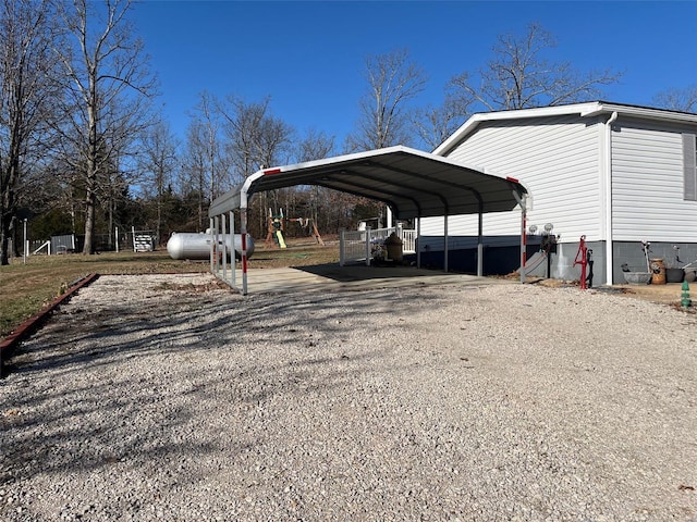 view of car parking featuring a detached carport, driveway, and fence