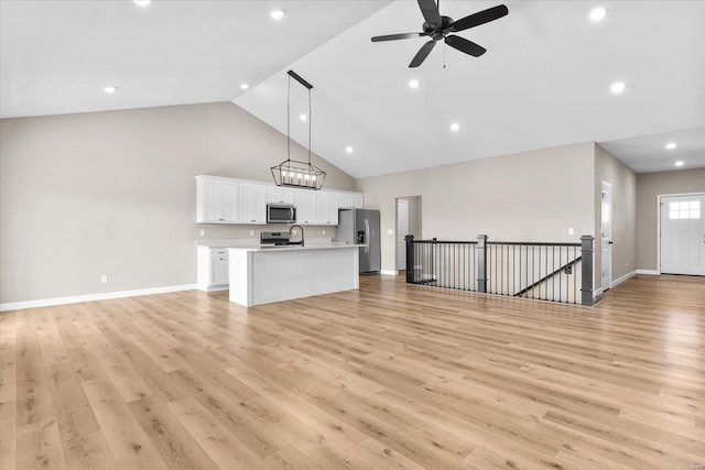 unfurnished living room with ceiling fan, baseboards, light wood finished floors, and high vaulted ceiling