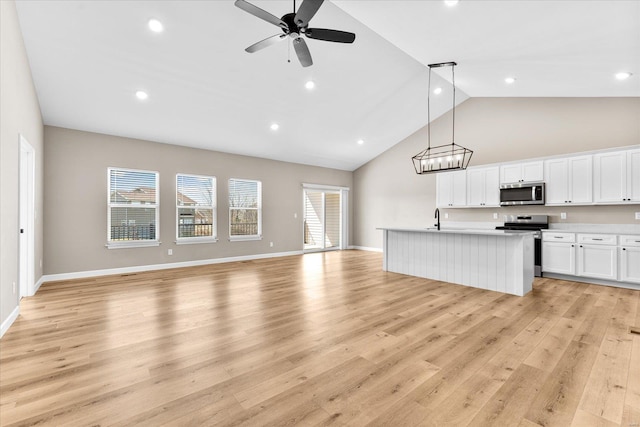 kitchen featuring open floor plan, light wood-style flooring, stainless steel appliances, and a kitchen island with sink