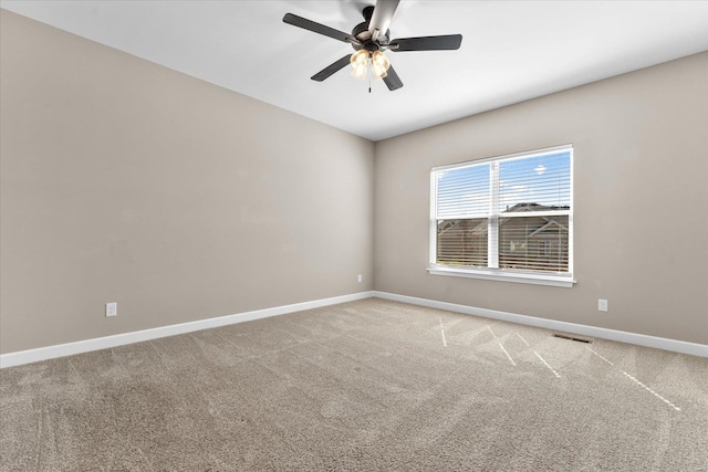 carpeted spare room featuring visible vents, baseboards, and ceiling fan