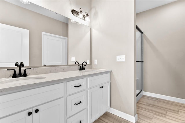 full bath with a sink, a stall shower, and wood finished floors