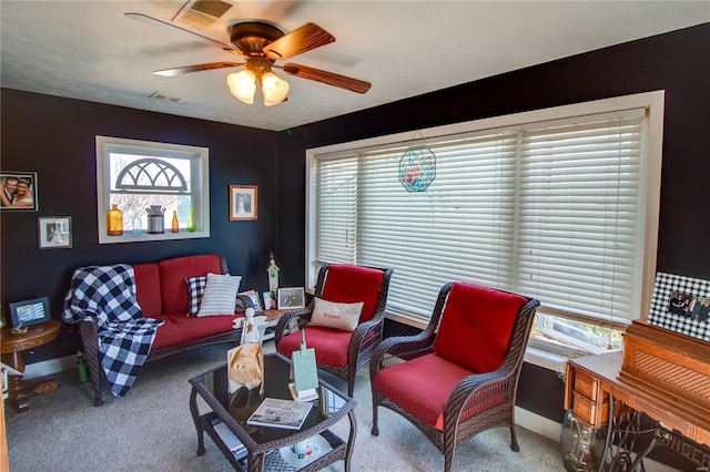 carpeted living room with visible vents, baseboards, and a ceiling fan