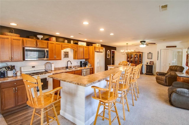 kitchen with a sink, light countertops, appliances with stainless steel finishes, a kitchen breakfast bar, and open floor plan