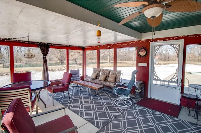 sunroom featuring beamed ceiling and a ceiling fan