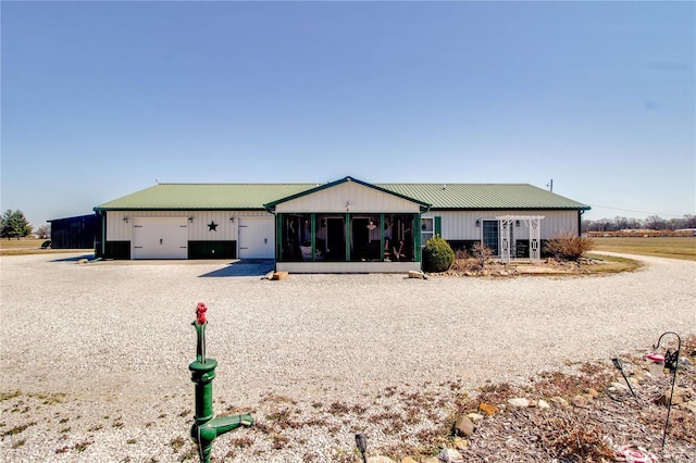 view of front of home with metal roof, a garage, and a sunroom