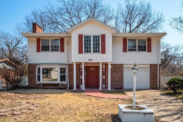 traditional-style home featuring brick siding, a garage, driveway, and a chimney