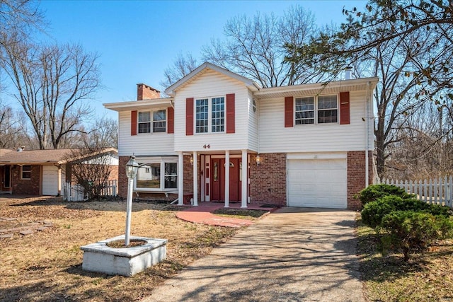 view of front of house featuring driveway, brick siding, a chimney, and fence