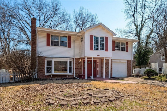 traditional-style house featuring brick siding, a chimney, an attached garage, and fence