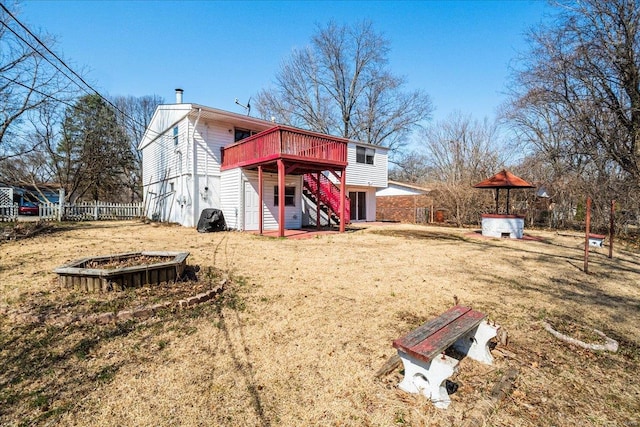 rear view of property featuring stairway, a lawn, a wooden deck, and fence