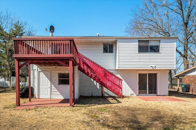 back of house with stairs, a yard, brick siding, and a wooden deck