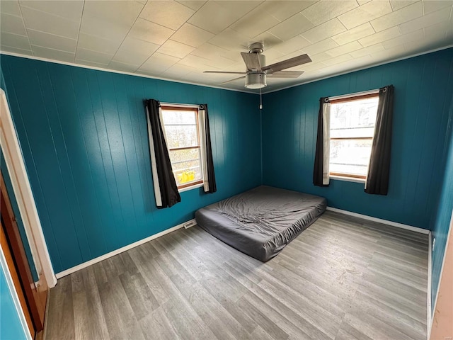 unfurnished bedroom featuring wood finished floors, baseboards, and ceiling fan