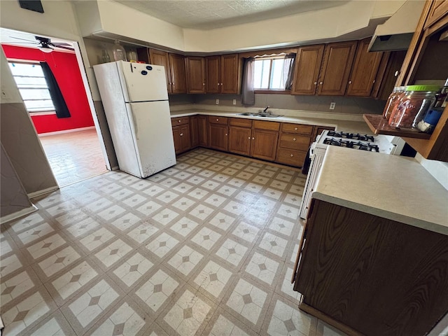 kitchen with a sink, white appliances, light floors, and light countertops