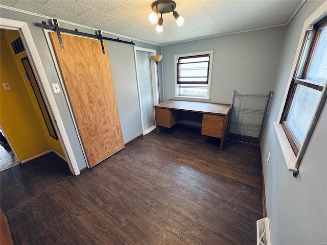 interior space featuring a barn door, baseboards, and dark wood-style floors