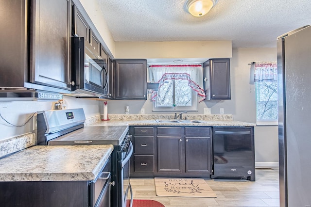 kitchen featuring a sink, light wood-style flooring, appliances with stainless steel finishes, and a wealth of natural light