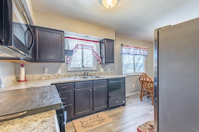 kitchen featuring dishwasher, a wealth of natural light, freestanding refrigerator, and a sink