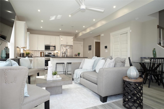 living area featuring recessed lighting, a ceiling fan, and light wood finished floors