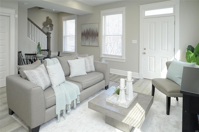 living area featuring stairs, baseboards, and light wood finished floors