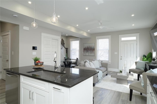 kitchen with light wood-type flooring, a sink, open floor plan, recessed lighting, and white cabinets