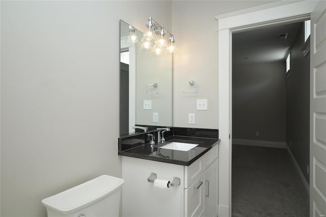 half bath featuring vanity, toilet, and baseboards