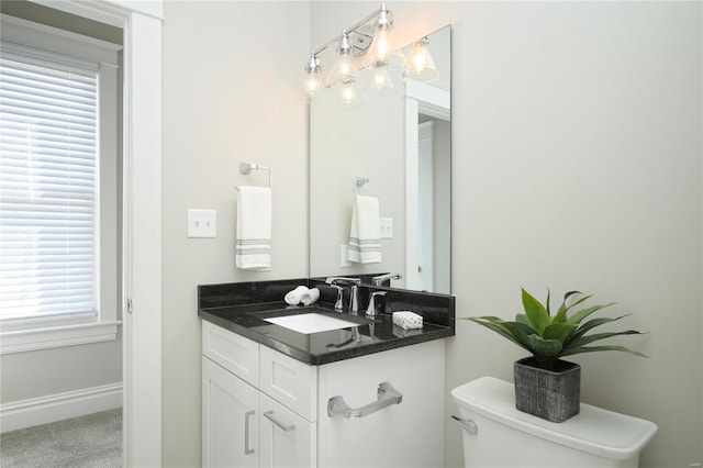 half bath with baseboards, toilet, and vanity