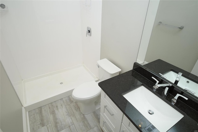 bathroom with vanity, toilet, a shower, and wood finish floors