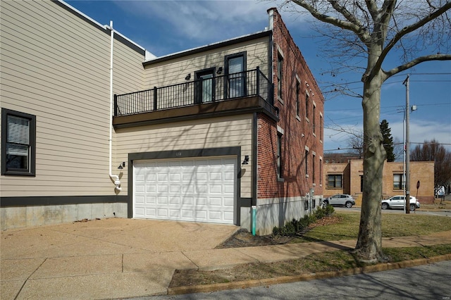 view of front of property featuring concrete driveway, a balcony, and a garage