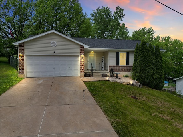 ranch-style house featuring a lawn, an attached garage, concrete driveway, and brick siding