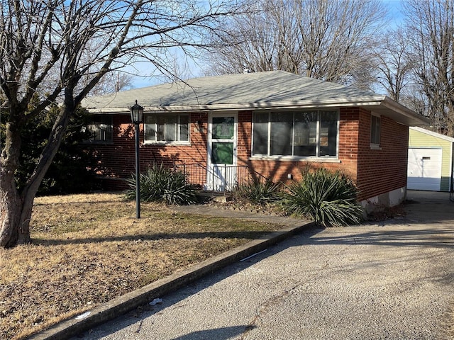 view of front of home with a garage, an outbuilding, and brick siding