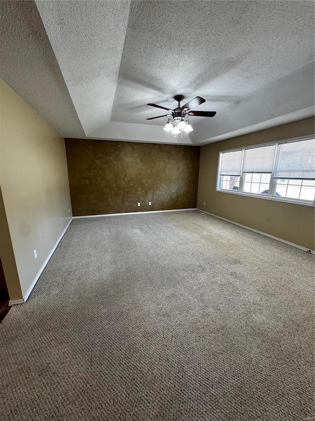 carpeted spare room featuring ceiling fan, a textured ceiling, and baseboards